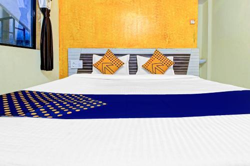 ein Bett mit orangefarbenen und blauen Kissen darauf in der Unterkunft SPOT ON Shreekrupa in Mahabaleshwar