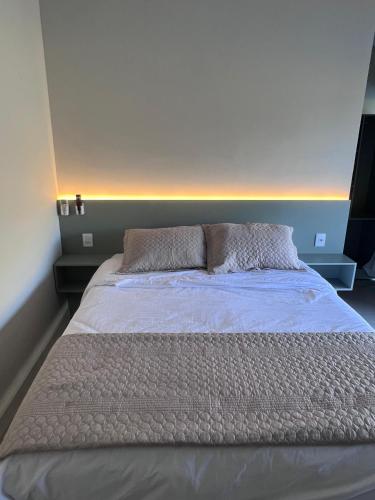 1 cama grande en un dormitorio con colcha blanca en Pousada Vista do Voo, en Brumadinho