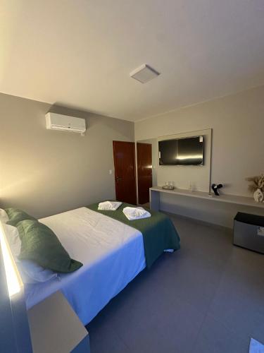 a bedroom with a large bed and a television at Pousada Vista do Voo in Brumadinho
