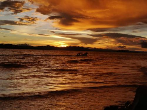 a boat in the water at sunset on the beach at Nómadas del Pacífico in Tapantí