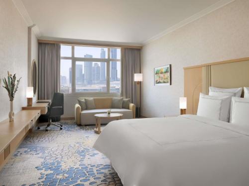 a hotel room with a large bed and a couch at Swissôtel Al Murooj Dubai in Dubai