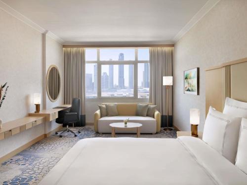 ドバイにあるSwissôtel Al Murooj Dubaiの大きなベッドとソファのあるホテルの部屋