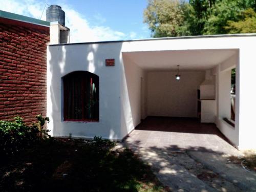 a white garage with a door and a brick wall at Casita de los recuerdos in Villa Carlos Paz