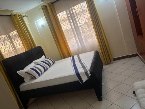 a bed in a room with two windows at Amtwapa 2bedroom apartment in Mtwapa