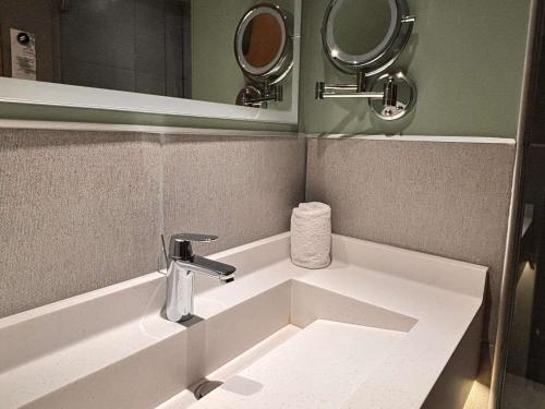 a bathroom with a sink and two mirrors at Novotel Monterrey Valle in Monterrey