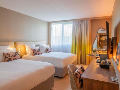 a hotel room with two beds and a television at Pullman Toulouse in Blagnac