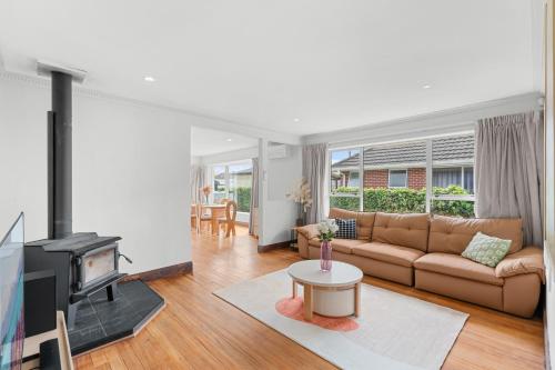 a living room with a couch and a fireplace at Peaceful four bedroom holiday house near airport in Christchurch