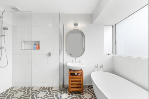 a white bathroom with a sink and a mirror at Peaceful four bedroom holiday house near airport in Christchurch