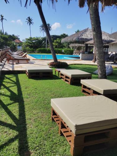 a group of benches in the grass near a pool at Eco paradise 134 in Cumbuco