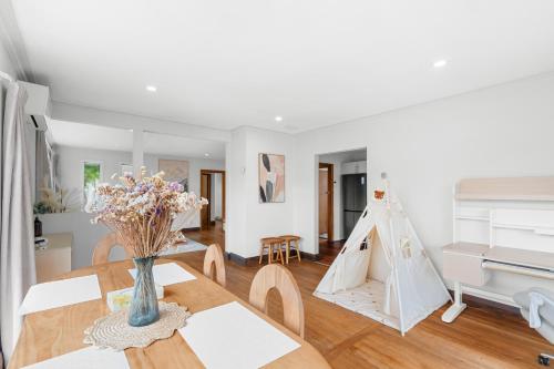 a living room with a table and a piano at Peaceful four bedroom holiday house near airport in Christchurch