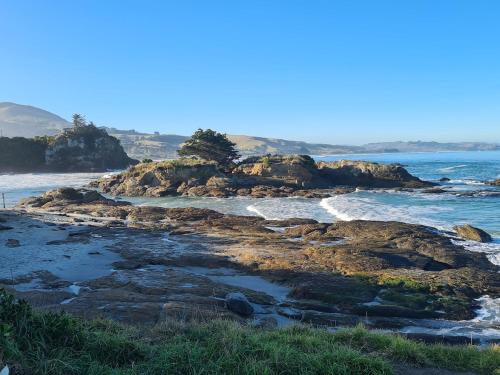 a beach with rocks and the ocean at Sleeps 3 to 4 - - 200m from beach in Dunedin