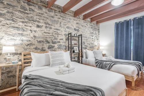 two beds in a room with a stone wall at Spacious 2BR Downtown - Vintage Charm Sleeps 10 in Montréal