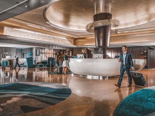 un homme marchant dans un hall avec ses bagages dans l'établissement Pullman Brisbane King George Square, à Brisbane