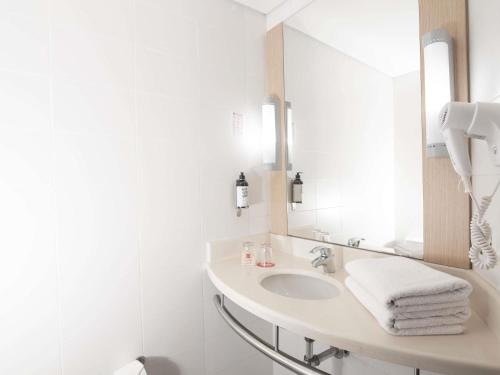 ein weißes Badezimmer mit Waschbecken und Spiegel in der Unterkunft ibis Medellin in Medellín