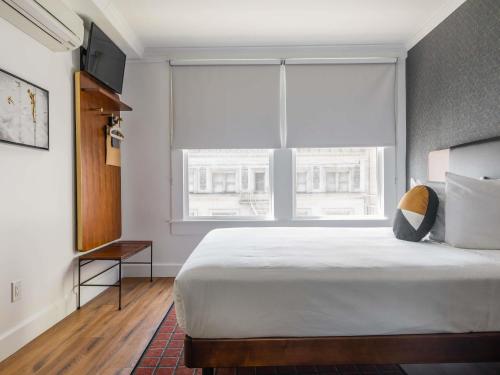 a bedroom with a large bed and a large window at Hotel Stratford San Francisco - Handwritten Collection in San Francisco