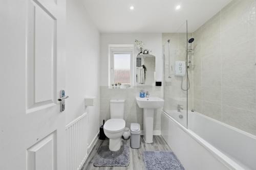 a white bathroom with a toilet and a sink at Lara's 4 Bedroom House near Coventry in Coventry