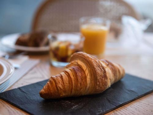 a croissant on a black plate on a table with orange juice at The Classic Hotel Nicosia - Handwritten Collection in Nicosia