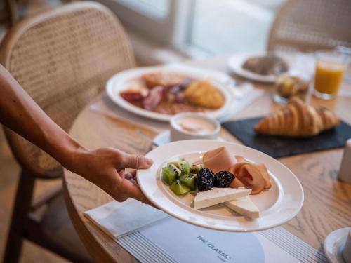 a person holding a plate of food on a table at The Classic Hotel Nicosia - Handwritten Collection in Nicosia