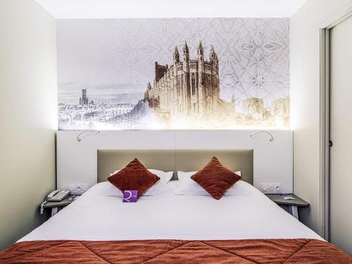 a bedroom with a bed with a painting on the wall at Mercure Albi Rives du Tarn in Albi