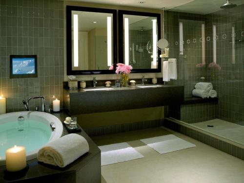 a bathroom with a tub and a sink and two mirrors at Hotel Sofitel Los Angeles at Beverly Hills in Los Angeles