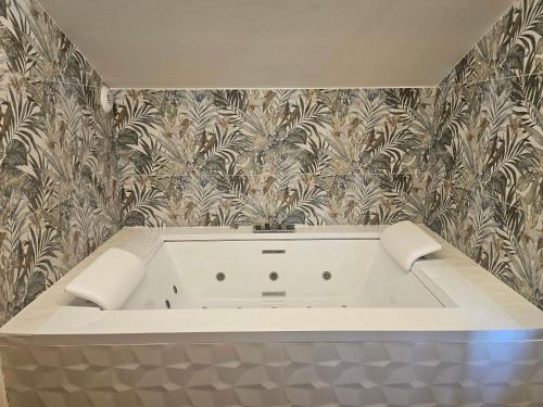 a white bath tub in a bathroom with wallpaper at Mercure Albi Rives du Tarn in Albi