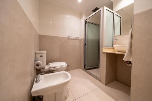 een badkamer met een toilet, een wastafel en een spiegel bij HOTEL REGIS in Buenos Aires