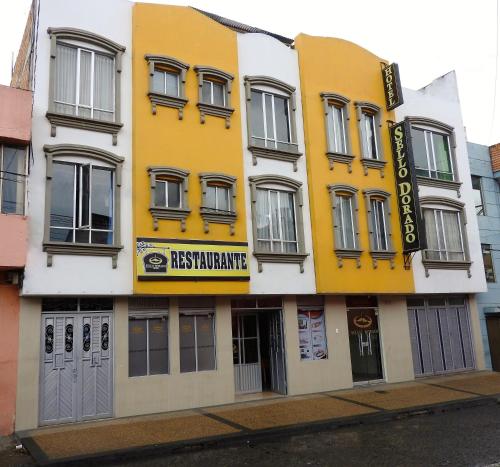 un edificio blanco y amarillo con un letrero. en Hotel Sello Dorado, en Pasto