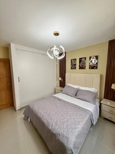 a bedroom with a large bed and a chandelier at Alma Ivet III 5min From The Airport & Boca Chica Beach in Monte Adentro