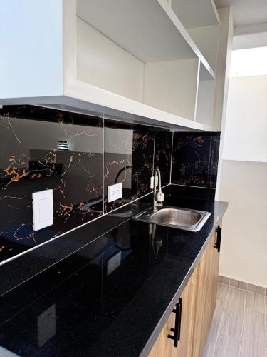 a kitchen with a black counter top and a sink at Alma Ivet III 5min From The Airport & Boca Chica Beach in Monte Adentro