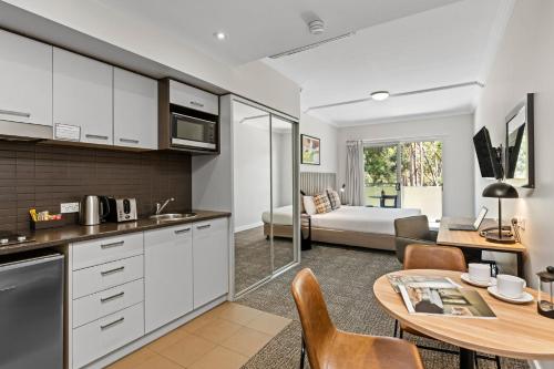a kitchen and living room with a table and a bed at Quest Campbelltown in Campbelltown