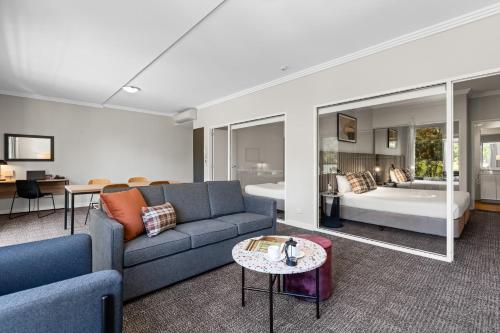 Una sala de estar con un sofá y un dormitorio. en Quest Campbelltown, en Campbelltown
