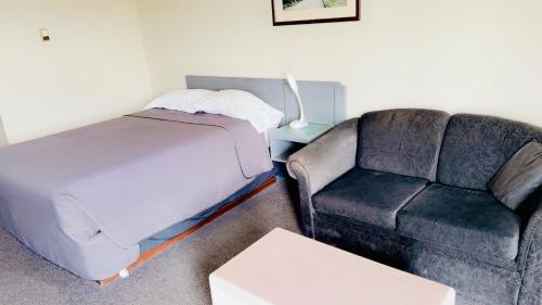 a room with a couch and a bed and a couch and a chair at Plains Motor Inn in Stettler
