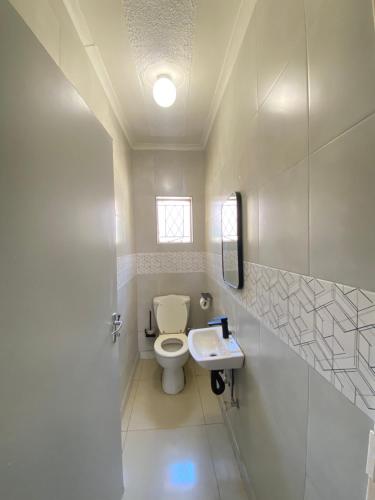 a bathroom with a toilet and a sink at The Cosy Retreat Guest House in Gaborone