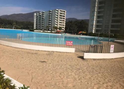 a large swimming pool next to a beach with buildings at Departamento Papudo laguna in Quinquimo