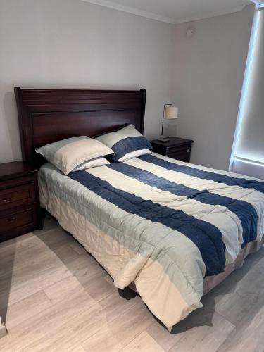 a bedroom with a large bed with blue and white sheets at Departamento en Papudo laguna con acceso a la playa in Quinquimo