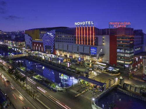 a night view of a city with a train station at Novotel Jakarta Mangga Dua Square in Jakarta