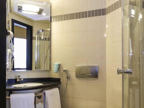 a bathroom with a sink and a shower with a mirror at ibis Sharq in Kuwait