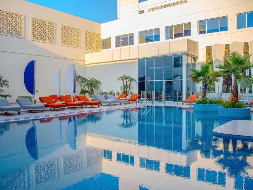 a swimming pool with orange chairs and a building at Novotel Dubai World Trade Centre in Dubai