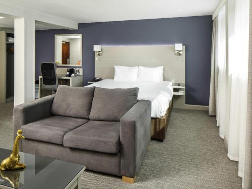 a hotel room with a bed and a couch at Mercure Manchester Piccadilly Hotel in Manchester
