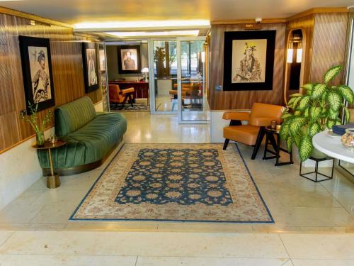a living room with a green couch and chairs at MUZE Hotel Dusseldorf - Handwritten Collection in Düsseldorf