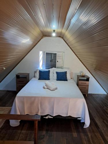 a bedroom with a large white bed with blue pillows at Chalé aconchegante à 300mts do mar in Arroio do Silva
