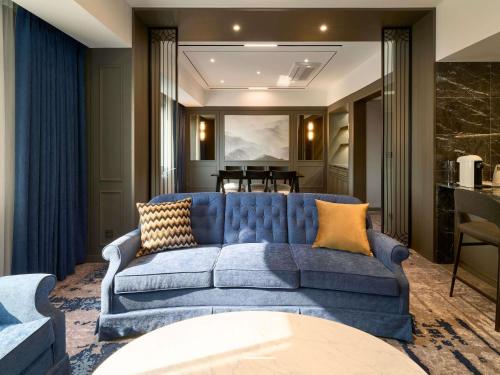 a blue couch in a living room with a table at Grand Mercure Imperial Palace Seoul Gangnam in Seoul