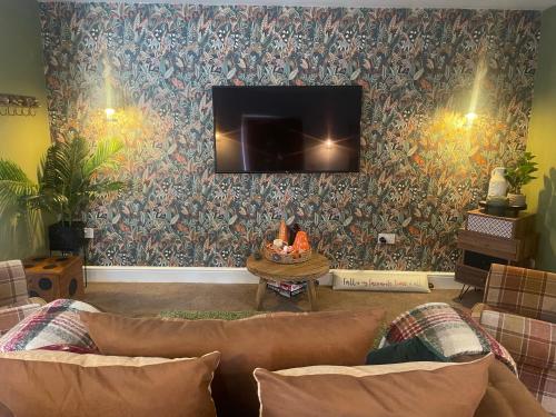 a living room with a couch and a tv on a wall at The Coachmans Cottage in Rock Ferry