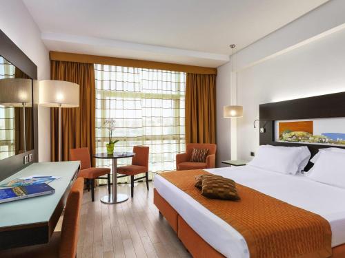 a hotel room with a large bed and a desk at Hotel Mercure Siracusa in Siracusa