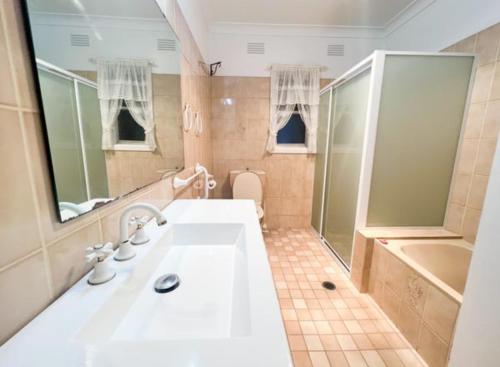 La salle de bains est pourvue d'un grand lavabo blanc et d'une douche. dans l'établissement Creswell Street Cottage, à West Wyalong