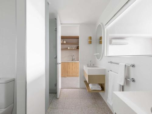 a white bathroom with a sink and a mirror at The Johnson Brisbane - Art Series in Brisbane