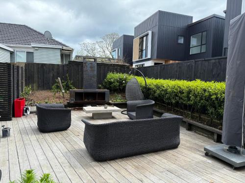 a patio with couches and a fire place in a backyard at Sunny St Heliers in Auckland