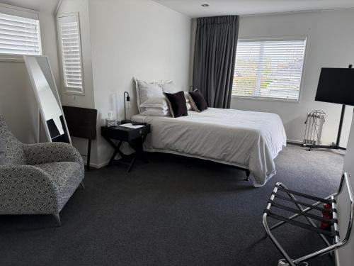 a bedroom with a bed and a chair and a couch at Sunny St Heliers in Auckland