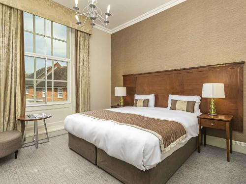 ソールズベリーにあるMercure Salisbury White Hart Hotel & Apartmentsの大きなベッドと大きな窓のある寝室