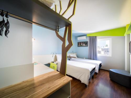 a hotel room with two beds and a tree on the wall at ibis Styles Curitiba Centro Civico in Curitiba